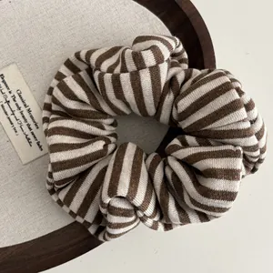 Close-up of brown and white striped knit scrunchie with soft ribbed texture on a tray