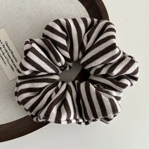 Detail view of a knitted striped hair scrunchie with brown and beige texture on a tray