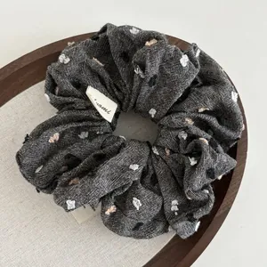 Close-up of textured scrunchie with colorful polka dots and a fabric label on wood