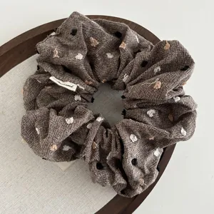Close-up of brown linen scrunchie with colorful dots and a small woven side label
