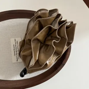 Close-up of caramel leather pleated banana hair clip with fine stitching on fabric base