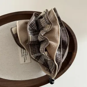 Makro-Detail der braunen karierten Haarspange mit plissierter Textur und Stoffgewebe