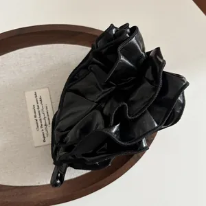 Detail of elegant black pleated faux leather banana clip with braided edge on a tray