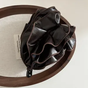 Macro view of dark brown pleated leather banana clip with elegant ruffled textures