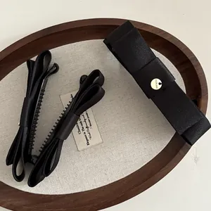 Détails de nœuds à cheveux en satin noir avec boucle en métal doré sur plateau en bois