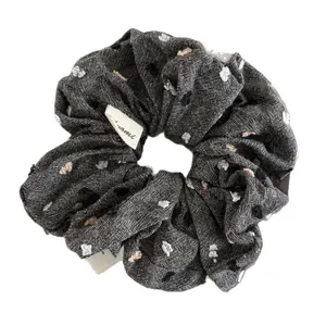 Dark grey scrunchie with white dots and textured fabric on a white background