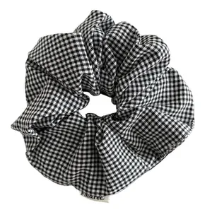 Klassieke zwart-witte gingham scrunchie met geweven label op een witte achtergrond