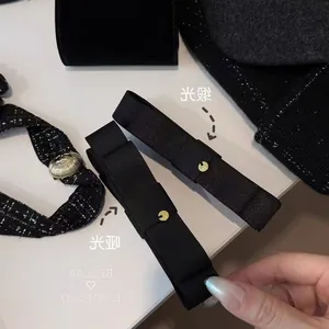 Détail des barrettes nœud noires en satin brillant et mat avec boucles dorées chic