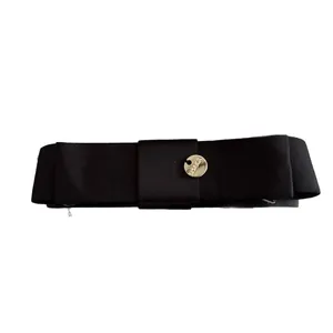 Barrette à cheveux élégante en satin noir avec emblème rond en métal doré sur fond blanc
