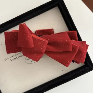 Close-up of a red layered velvet bow hair clip with sparkling gold glitter details