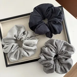 Close-up of three knit scrunchies in navy and grey with detailed ribbed texture on a tray