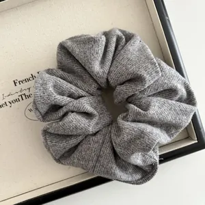 Detailed macro view of gray knitted scrunchie fabric texture on a white display board