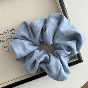 Detailed close-up of light blue knitted scrunchie fabric texture on a white tray