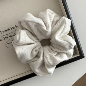 Close-up of cream ribbed knit scrunchie with textured fabric on a vintage tray
