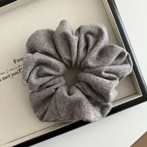 Close-up of a grey striped knit scrunchie on a tray showing soft fabric texture