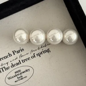 Détail de quatre grandes perles crème sur une pince à cheveux rétro dans un coffret