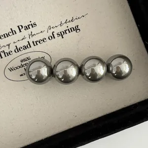 Vue rapprochée de quatre perles métalliques effet miroir sur une barrette à ressort