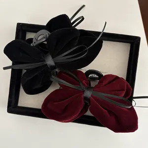 Detail of elegant velvet bow hair claws in black and burgundy with satin ribbons