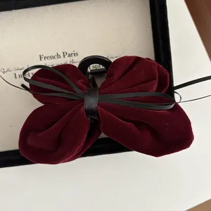 Macro detail of wine red velvet bow hair claw clip with black satin ribbon accent