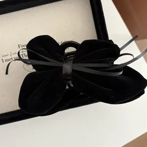 Detail of elegant black velvet bow hair claw clip with satin ribbon on vintage box