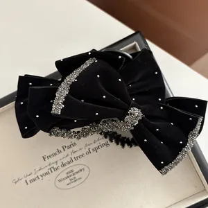 Close-up of elegant black velvet bow hair clip with sparkling silver rhinestone trim