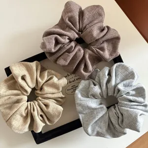 Three soft knitted scrunchies in coffee, beige and grey colors displayed on a wooden tray