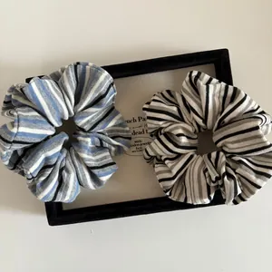 Two retro striped knit scrunchies in blue and black colors displayed on a jewelry tray