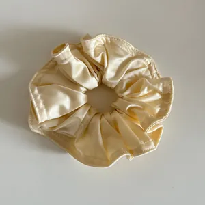 Detailaufnahme des champagnerfarbenen Satin-Scrunchies mit seidiger Textur und Nähten