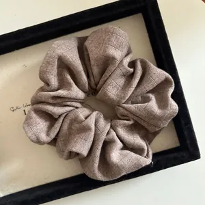Close-up of mocha brown knitted scrunchie with soft ribbed texture and pleated detail