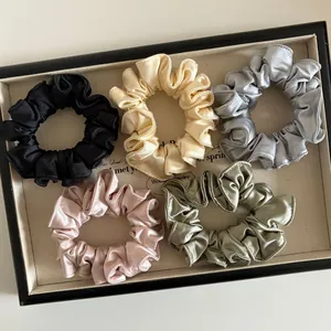 Lot de 5 chouchous en satin soyeux aux tons neutres sur un plateau de présentation bijoux