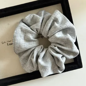 Detailed view of light gray ribbed knit fabric texture on an elastic scrunchie hair tie