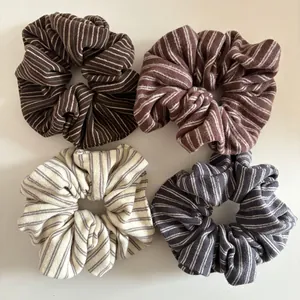 Detail of four striped knit hair scrunchies in coffee, brown, beige and grey colors