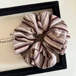 Detail of retro striped knit scrunchie with coffee and lavender tones in a display box