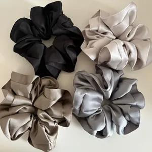 Detail of four premium satin scrunchies with elegant glossy texture and ruffled edges