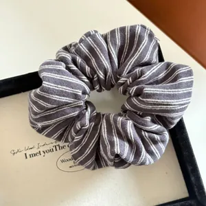 Detailed view of the soft knitted texture and grey striped pattern on this scrunchie