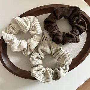 Trois chouchous minimalistes en maille côtelée crème et marron sur plateau