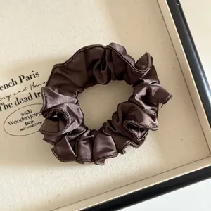 Détail d'un chouchou en satin marron foncé avec des plis denses et une texture soyeuse