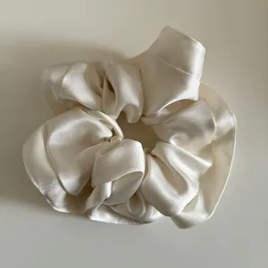 Detailed view of the soft cream satin fabric texture on this oversized hair scrunchie