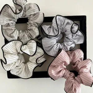 Detail of four striped scrunchies in assorted colors with handmade labels on a tray