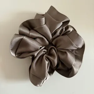 Macro shot of large satin scrunchie showing premium silky texture and champagne folds