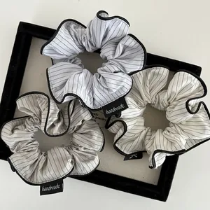 Three-piece set of striped scrunchies in blue, beige, and white with handmade labels