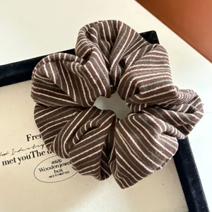Detailed close-up of dark brown striped fabric scrunchie with rich elastic texture