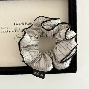 Close-up of a striped scrunchie with black piping and a handmade woven label