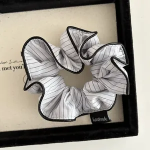 Detail showing white and black striped fabric hair scrunchie with handmade woven label