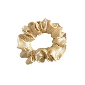 Chouchou élégant en satin champagne avec bords plissés et texture soyeuse de luxe