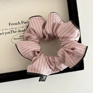 Close-up of pink striped scrunchie with bow label in a black velvet jewelry box