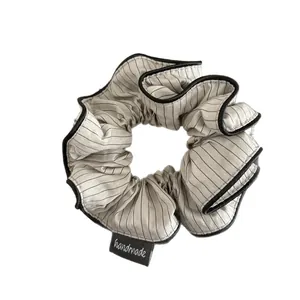 Striped beige scrunchie with black trim and handmade label for elegant ponytails
