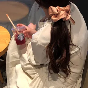 Detail of silk satin scrunchie in champagne gold on long wavy hair in a cozy cafe
