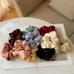 10-piece colorful silk satin scrunchies set displayed on a magazine and marble table