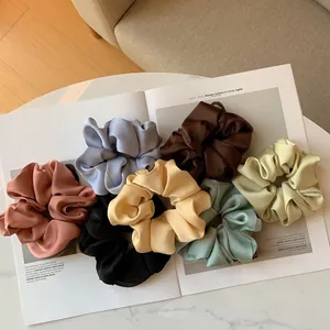 Set di 7 elastici per capelli in seta opaca colorata disposti su una rivista di moda